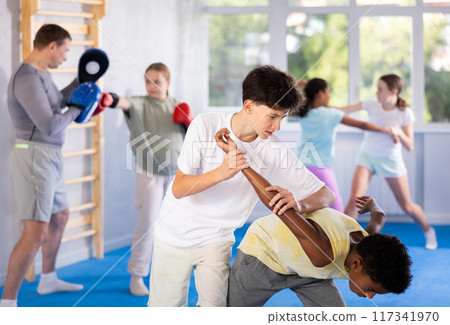 Teenager practicing painful armlock in sparring during self defence training 117341970