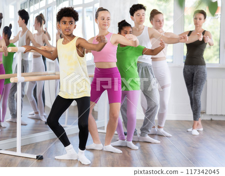 Dark-skinned teenage boy practicing demi plie at ballet barre Dark-skinned teenage boy practicing demi plie at ballet barre 117342045