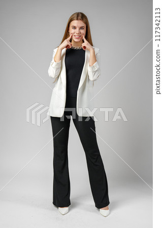 Woman Holding Finger to Smile in Studio 117342113