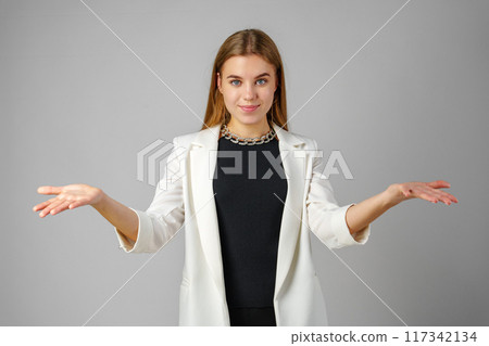 Young Woman Expressing Confusion With Hands Raised Against a Grey Background Young Woman Expressing Confusion With Hands Raised Against a Grey Background 117342134
