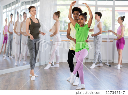 Teenage girl practicing ballet positions in pair with boy in dance studio 117342147