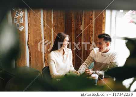 Two People Engaged in Casual Conversation at a Cozy Cafe During the Day 117342229