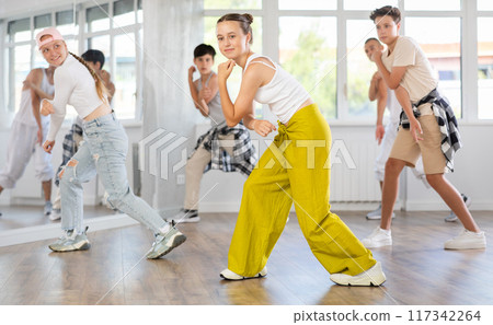 Teenagers in casual clothes are training together to dance hip-hop and breakdancing in dance center Teenagers in casual clothes are training together to dance hip-hop and breakdancing in dance center 117342264