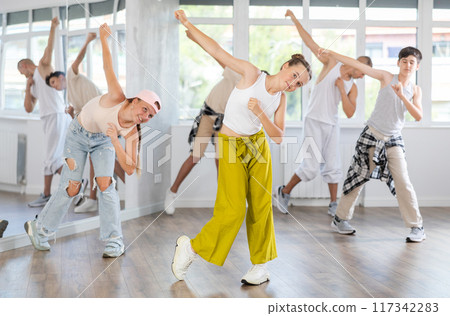 Teenage girl practicing hip hop slide moves in training hall Teenage girl practicing hip hop slide moves in training hall 117342283