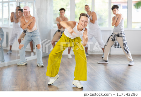 Teenage girl dancing hip-hop against background of group members Teenage girl dancing hip-hop against background of group members 117342286