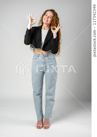 Young Woman Giving Ok Sign on gray background Young Woman Giving Ok Sign on gray background 117342349