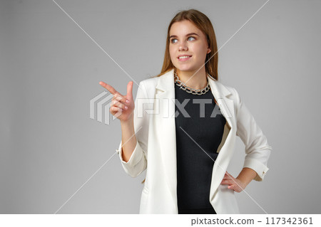 Confident Young Businesswoman Presenting With Hand Gesture in Studio Setting 117342361