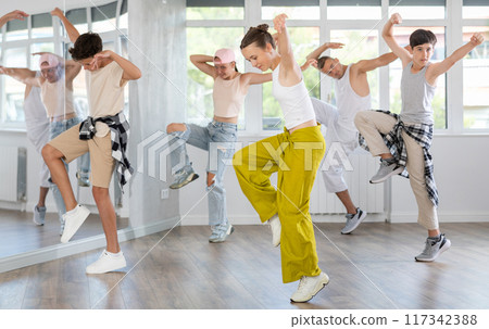 Teenage girl practicing hip hop reject step in training hall 117342388