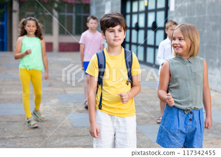 Positive tweenagers walking outside school building 117342455
