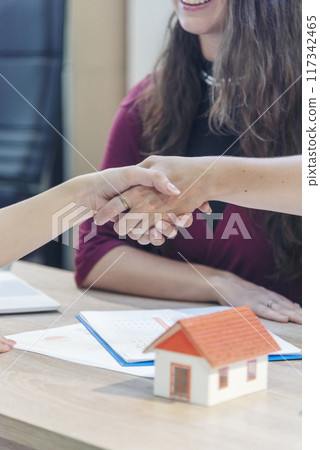 Close up Businesswoman shakes hands customer dealing real estate house agent signing contract. Diversity women agent hands office desk. Crop Women handshake sign on insurance mortgage sale document 117342465