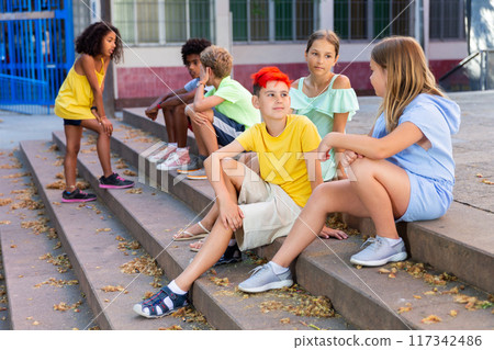 Children talking together while sitting on stairs outdoors 117342486