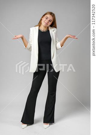 Young Woman Expressing Confusion With Hands Raised Against a Grey Background Young Woman Expressing Confusion With Hands Raised Against a Grey Background 117342520
