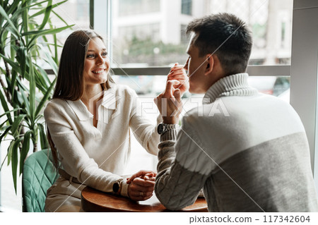 Two Friends Enjoying Casual Conversation Over Coffee at a Modern Cafe During Daytime Two Friends Enjoying Casual Conversation Over Coffee at a Modern Cafe During Daytime 117342604