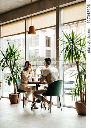 Couple Engaged in Conversation at a Cozy Cafe During Daytime 117342608
