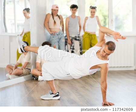 Male trainer showing breakdancing to group of teenagers Male trainer showing breakdancing to group of teenagers 117342609