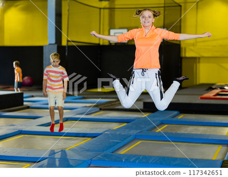 Girl jumping on trampoline park in sport center Girl jumping on trampoline park in sport center 117342651