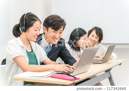 在補習班/學校教室裡由老師教用電腦和耳機學習的小學、初中和高中兒童 117342668