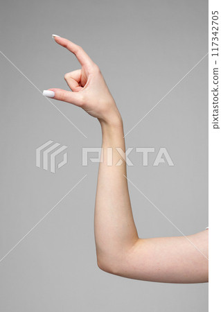 Female hand gesturing sign against gray background 117342705