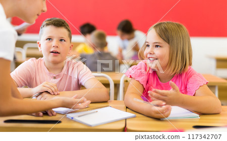 Interested preteen pupils discussing learning material in groups 117342707