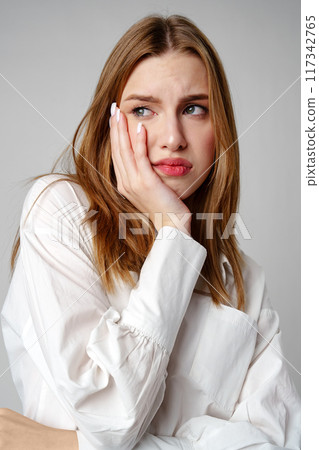 Young Woman Exhibiting a Pensive Sad Expression in a Studio Young Woman Exhibiting a Pensive Sad Expression in a Studio 117342765