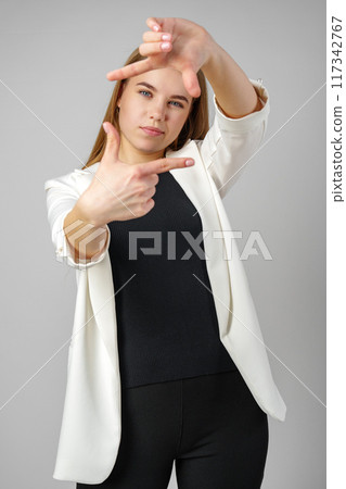 Young Woman Making Frame Gesture With Hands Against a Neutral Background 117342767