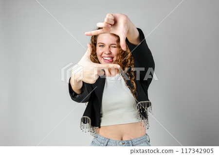 Woman Making Hand Gesture Picture Frame in Studio 117342905