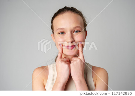 Young Woman Grimacing in Displeasure Against a Neutral Background 117342950