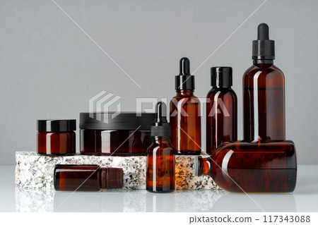 Set of brown glass bottles with essential oils on stand on gray background 117343088