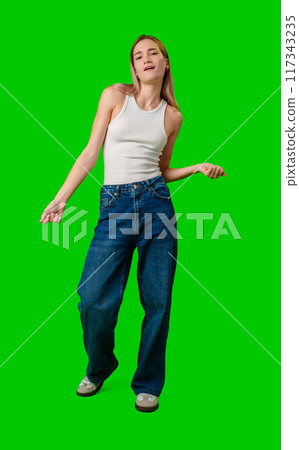Young Woman Dancing in Loose Jeans Against Green Screen Background 117343235