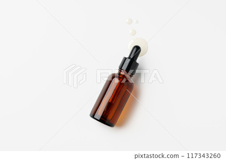 Brown Glass Dropper Bottle With White Liquid on a White Background 117343260