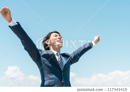 A young Asian businessman rejoicing under the blue sky (job change, victory, finding employment, quitting his job, taking on the challenge, working hard, achieving) 117343419