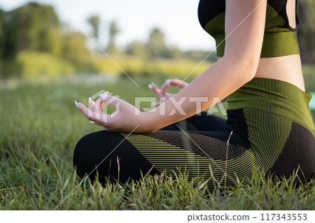girl practicing yoga at Root Bond, Mula Bandha poses on a mat in an outdoor park 117343553