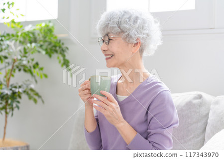 Senior woman relaxing on the sofa drinking coffee 117343970