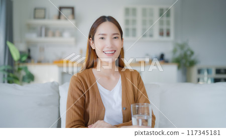 Portrait young asian woman smiling sitting on couch in living room and looking to camera 117345181