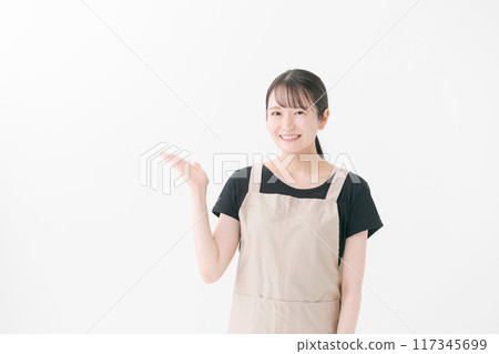 A woman in her twenties wearing an apron A woman in her twenties wearing an apron 117345699