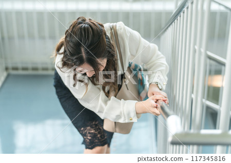 Business woman suffering from back pain on stairs (strained back, collagen disease, rheumatoid arthritis) 117345816