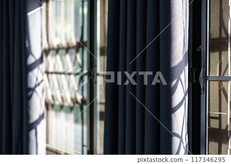 Shadow of the sun rays falling on the wall through the louvers during day. 117346295