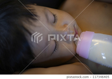 Sleeping baby with a milk bottle. Sleeping baby with a milk bottle. 117346405
