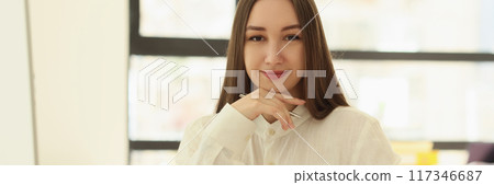 Happy female employee sitting at table in office 117346687