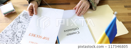 Military man holding in hands secret plans of Ukrainian counteroffensive operation Military man holding in hands secret plans of Ukrainian counteroffensive operation 117346805