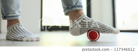 Woman massaging foot with ball to eliminate feet tension 117346812