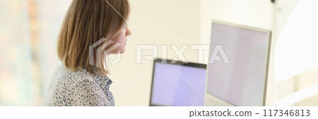 Woman sitting at workplace and working on laptop and pc in office Woman sitting at workplace and working on laptop and pc in office 117346813