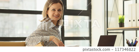 Smiling businesswoman posing at workplace in office Smiling businesswoman posing at workplace in office 117346822