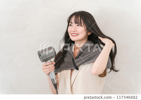 A woman blow-drying her hair with a hair dryer (hair care) A woman blow-drying her hair with a hair dryer (hair care) 117346882
