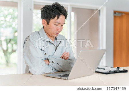 A young Asian businessman wearing work clothes working on a computer 117347469