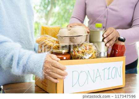 Volunteers putting various dry food in donation box for help people. Volunteers putting various dry food in donation box for help people. 117347596