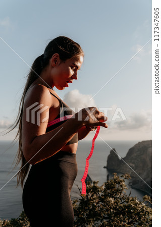 A woman is holding a pink tape measure and is measuring her breasts after morning fitness 117347605