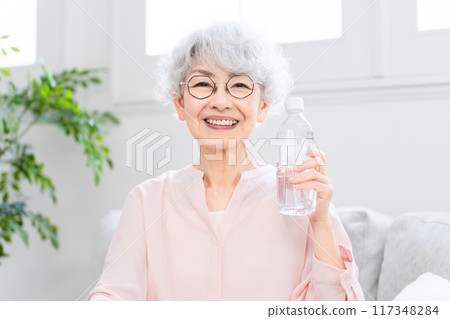 Senior woman drinking bottled water 117348284