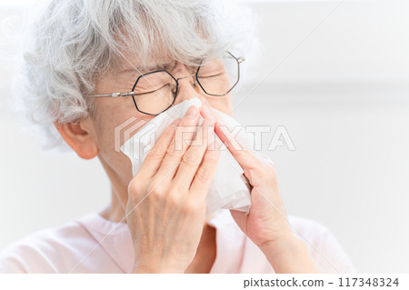 Senior woman biting his nose with tissue Senior woman biting his nose with tissue 117348324