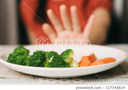 Little cute kid girl refusing to eat healthy vegetables. Children do not like to eat vegetables. 117348614